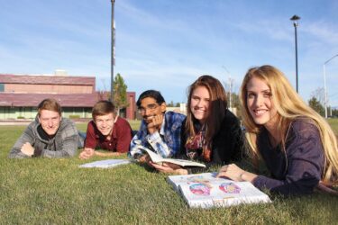 students smiling and laying in grass