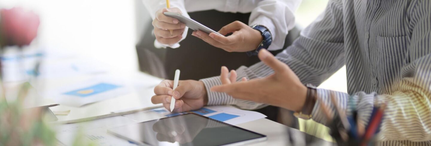 close up of two pairs of hands working with a cellphone and tablet