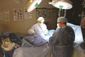 surgical technology students wearing scrubs conduct a mock operation in a classroom