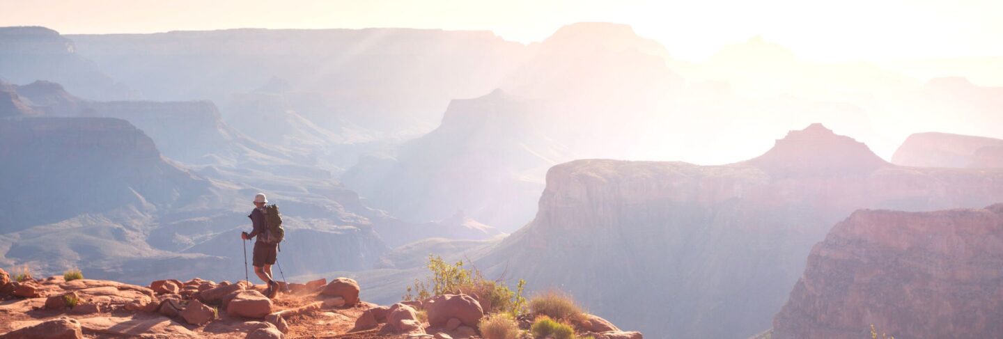 a hiker walks on the rim of the grand canyon