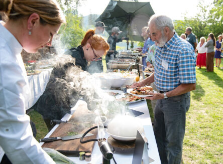 a man receives food from chefs at an outdoor kitchen