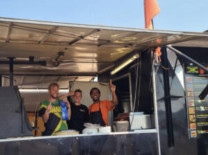 fiya grill staff pose in their food truck holding a blue first place ribbon