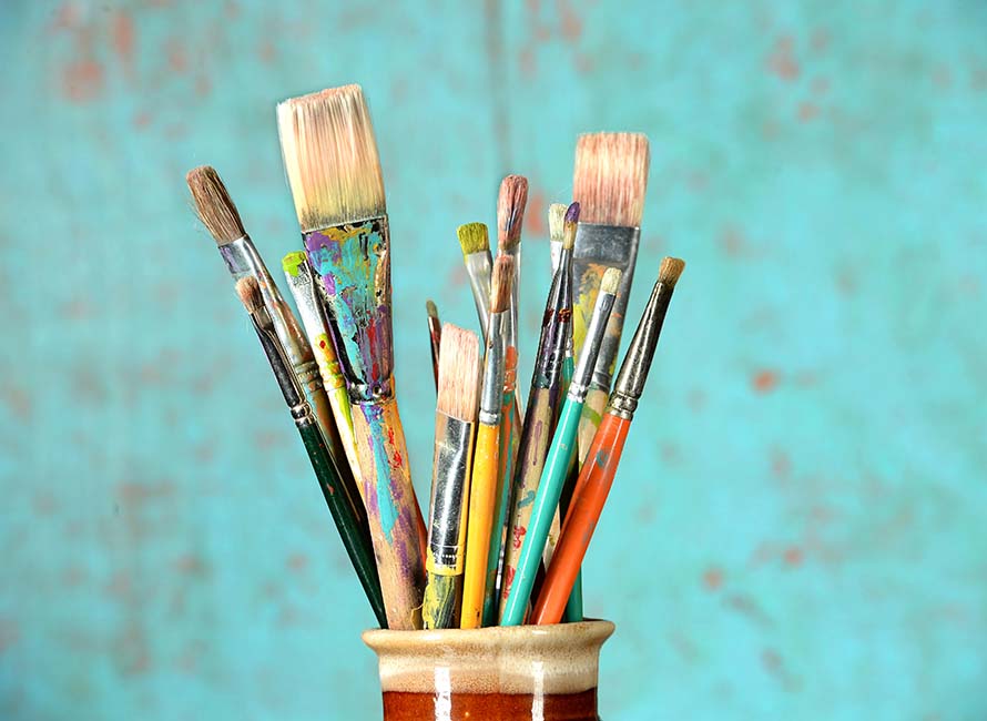 Artist paintbrushes in a jar over colorful background